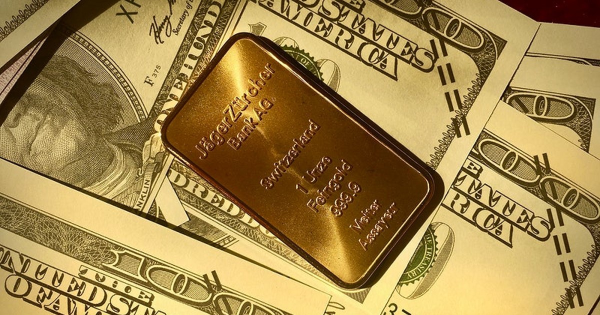 barra de una onza oro sobre billetes de cien dólares