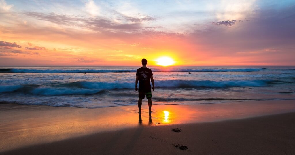 trader solitario en la playa descalzo observando el atardecer